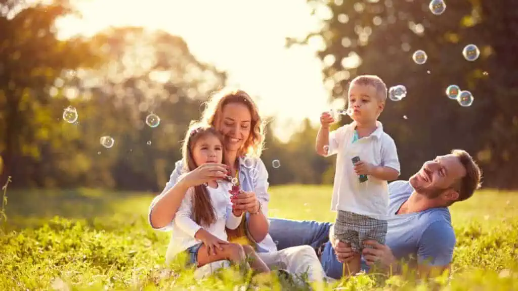 family blowing bubbles at the park happy