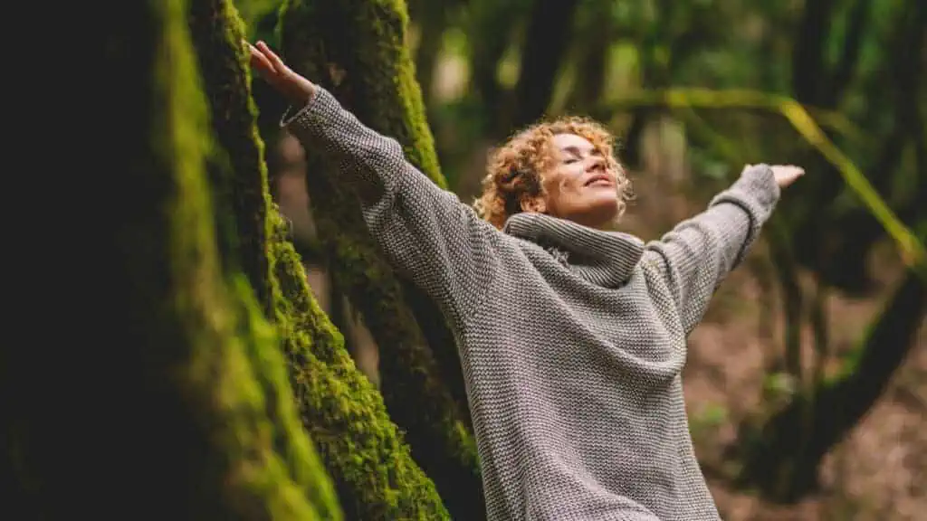 woman in nature taking a deep breathe, meditating