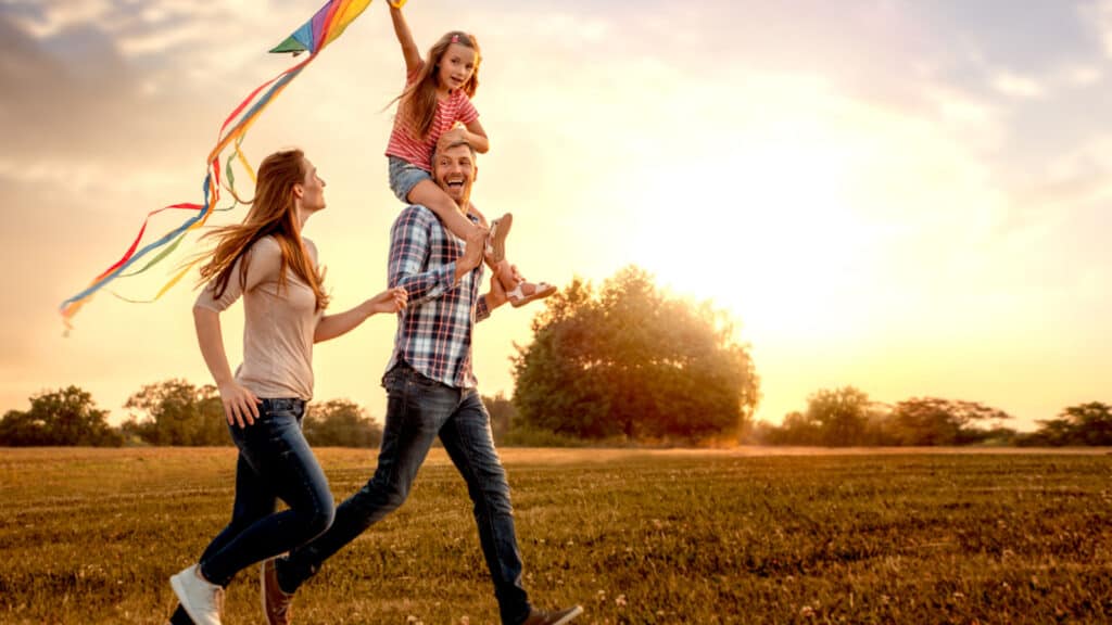 family happy flying a kite outside nature
