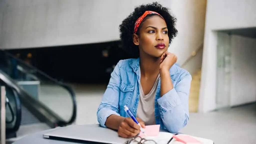 woman thinking at her desk writing