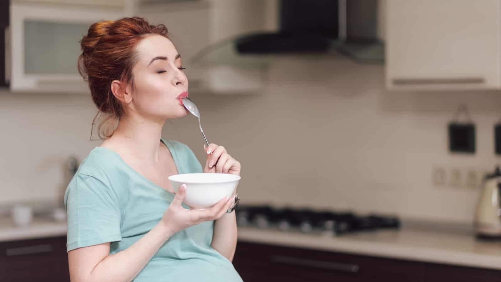 pregnant woman eating a bowl of food