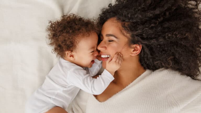 mom and baby on bed laughing