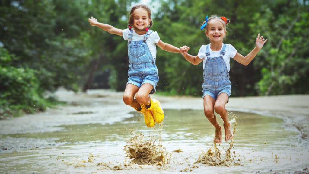 girls playing and jumping in the mud outdoors nature