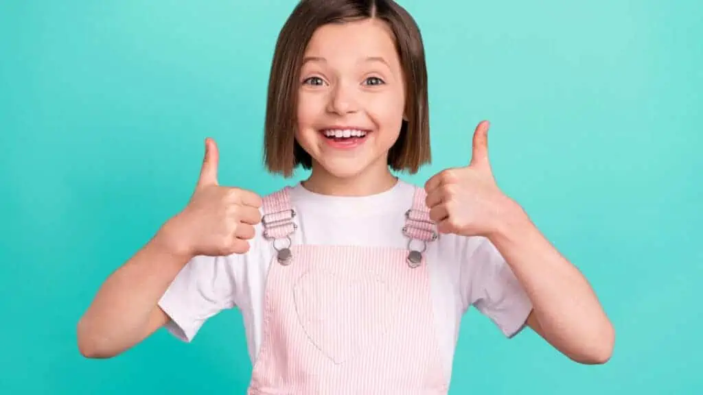 little girl in overalls happy thumbs up