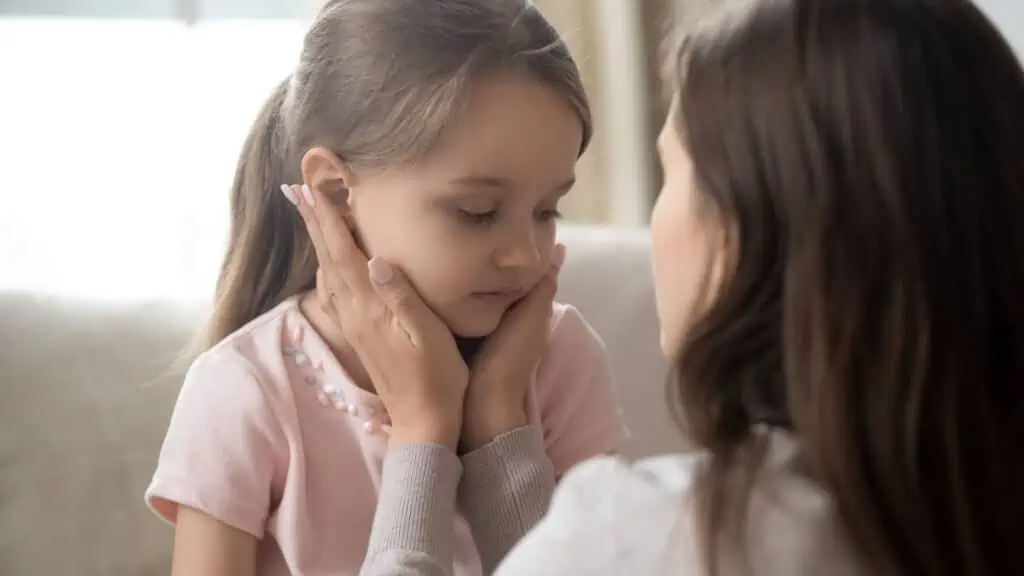 mom holding girls face showing empathy