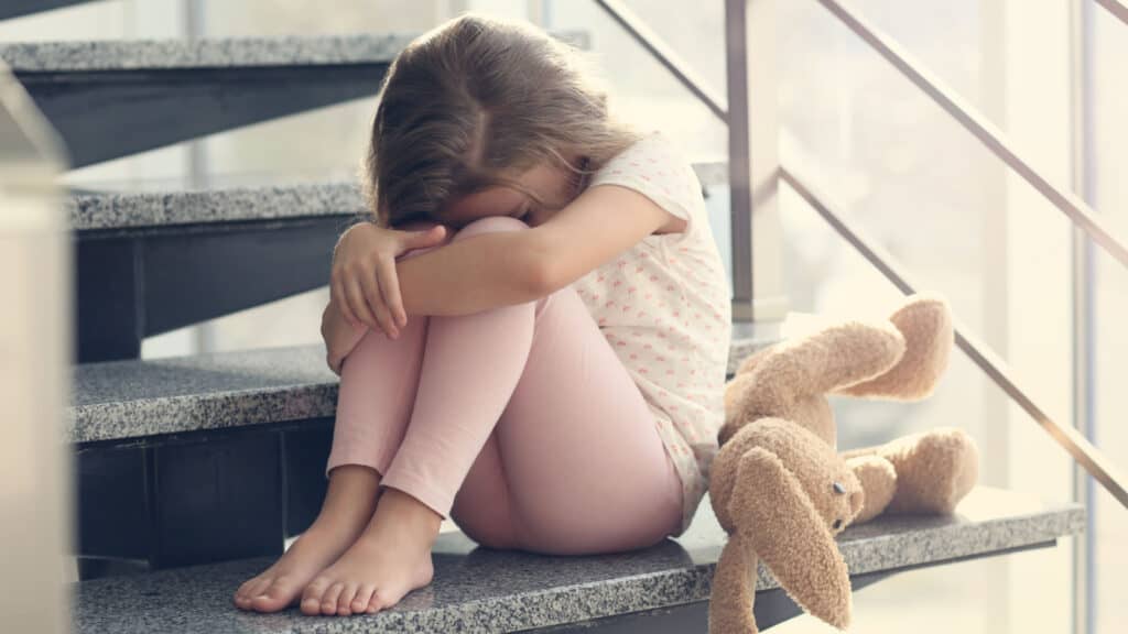 sad girl with teddy bear on stairs