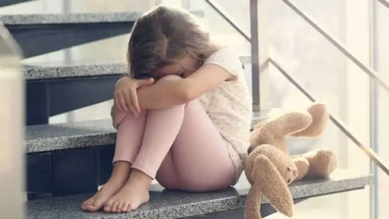 sad girl with teddy bear on stairs