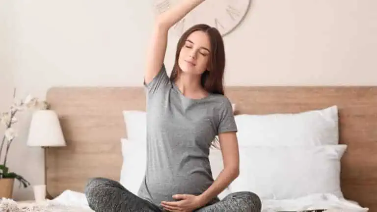 pregnant woman breathing stretching yoga happy in bed side reach