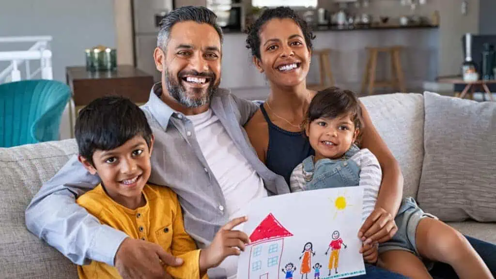 happy family of four holding a drawing