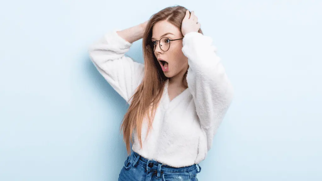 shocked woman hands on head glasses long hair