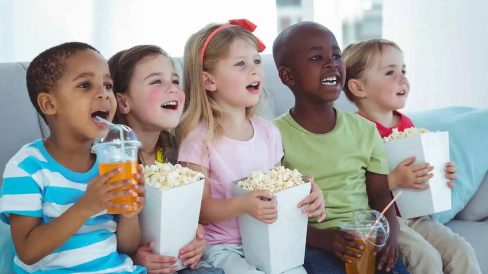 kids watching a movie with popcorn and drinks happy