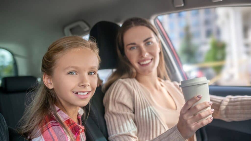 mom and daughter in the car with a coffee smiling