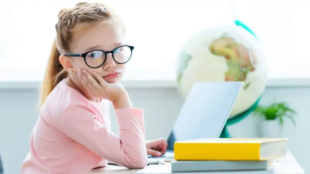 bored girl in glasses at the computer with books