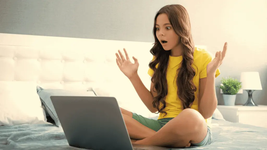 shocked woman girl at the computer sitting on a bed surprised