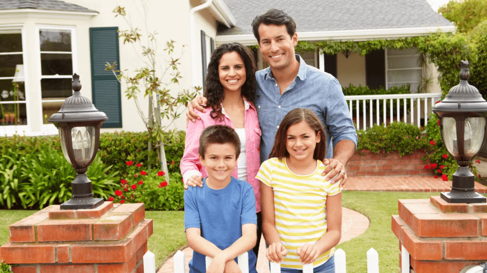 family in front of a house happy white picket fence