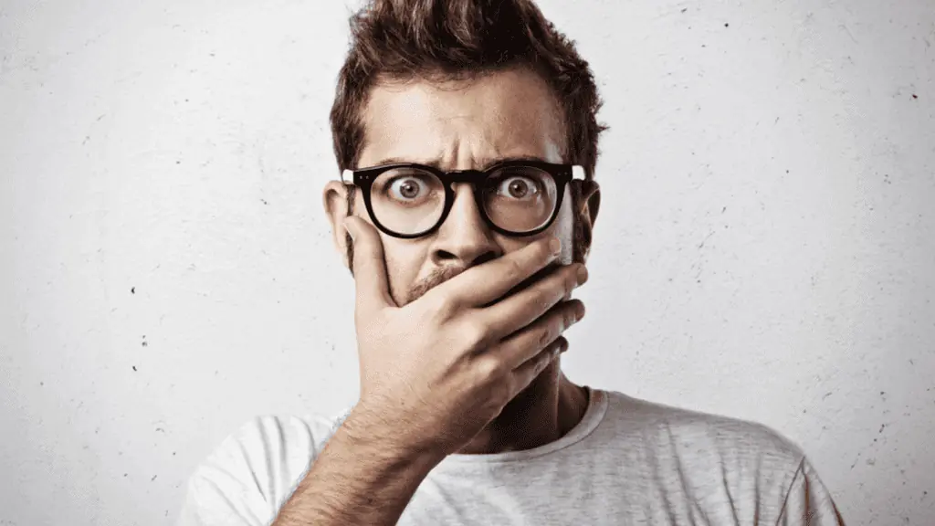 shocked man hand over mouth glasses