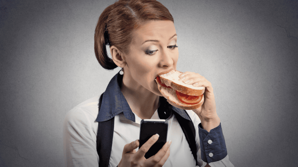 woman eating a sandwich on her phone