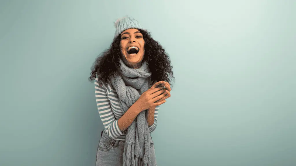 woman laughing winter hat and sweater blue