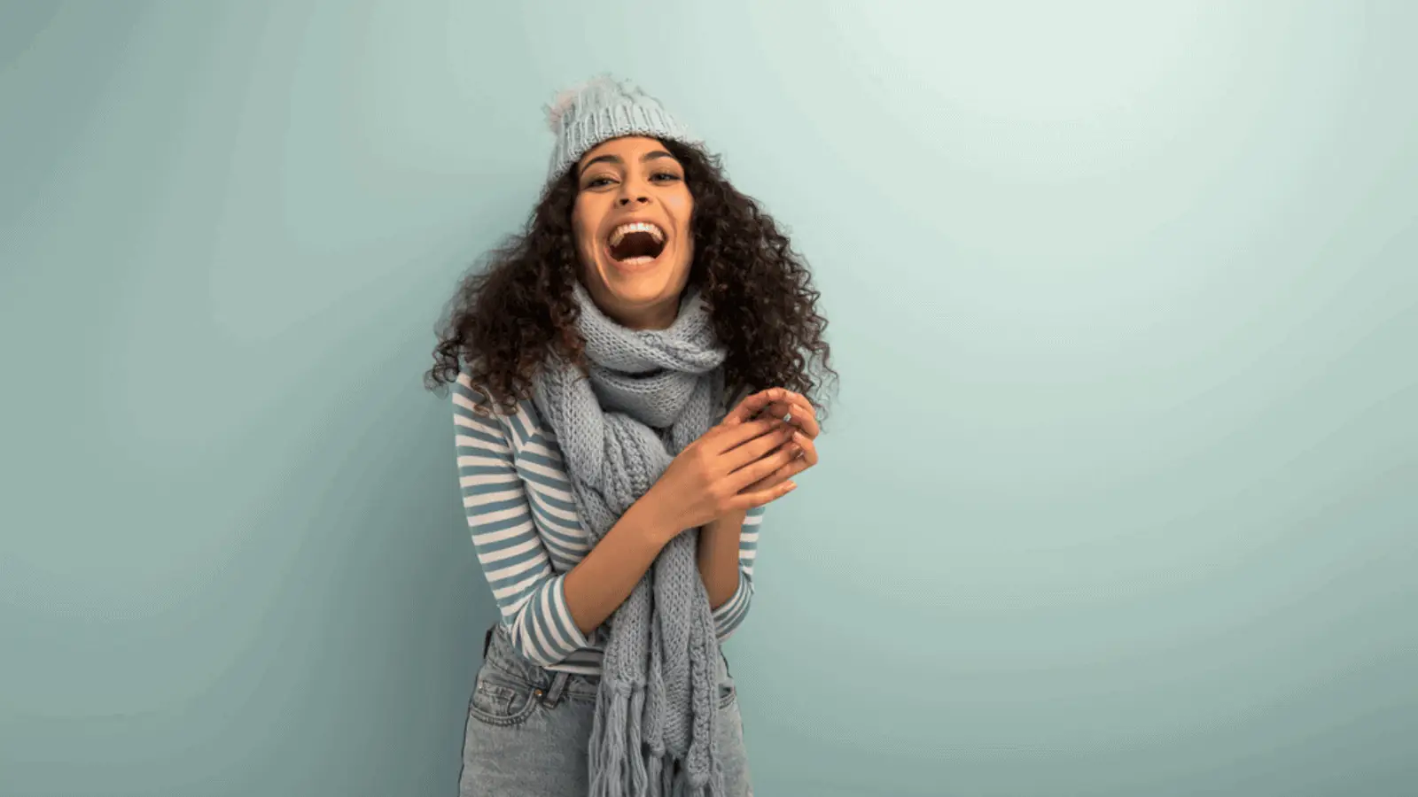 woman laughing winter hat and sweater blue