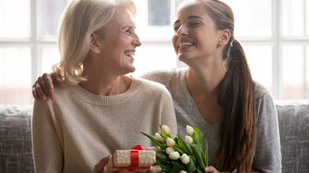 Woman giving her mother a gift and a flower