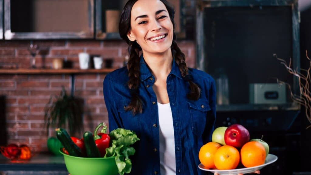 Woman in the kitchen holding fruits and vegetables
