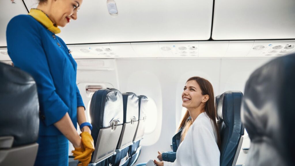 Woman passenger looking excited before the flight talking to flight attendant