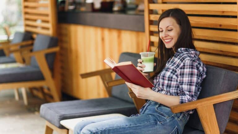 Woman reading a book in outdoors street summer coffee shop wooden cafe