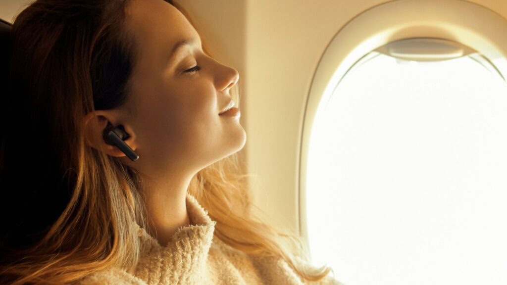 Woman sitting in airplane listening to music