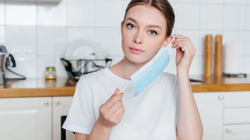 Young and attractive woman wearing medical mask at home