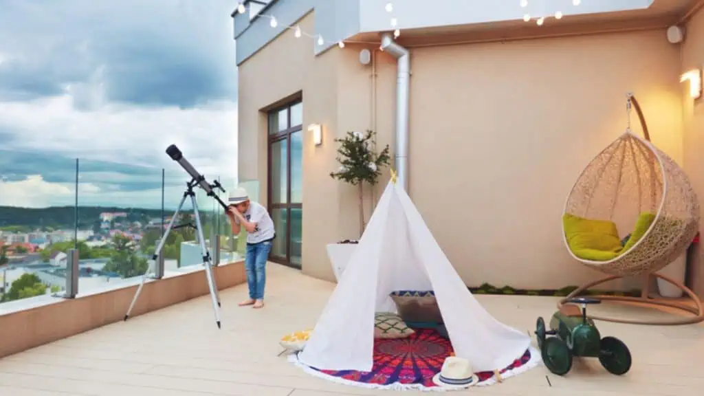 Young kid looking in telescope while playing games on rooftop