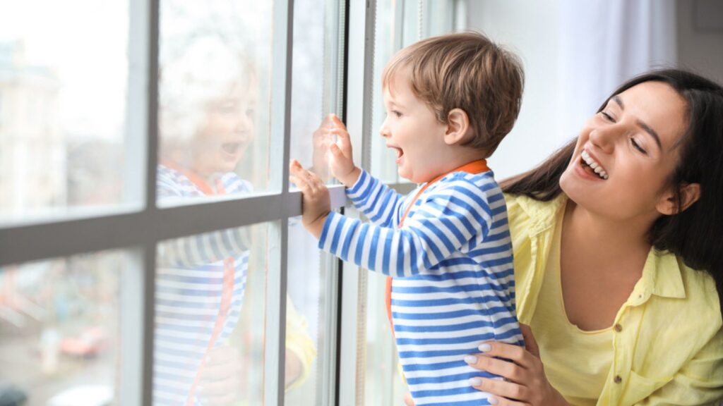Young mother with cute little son near window at home