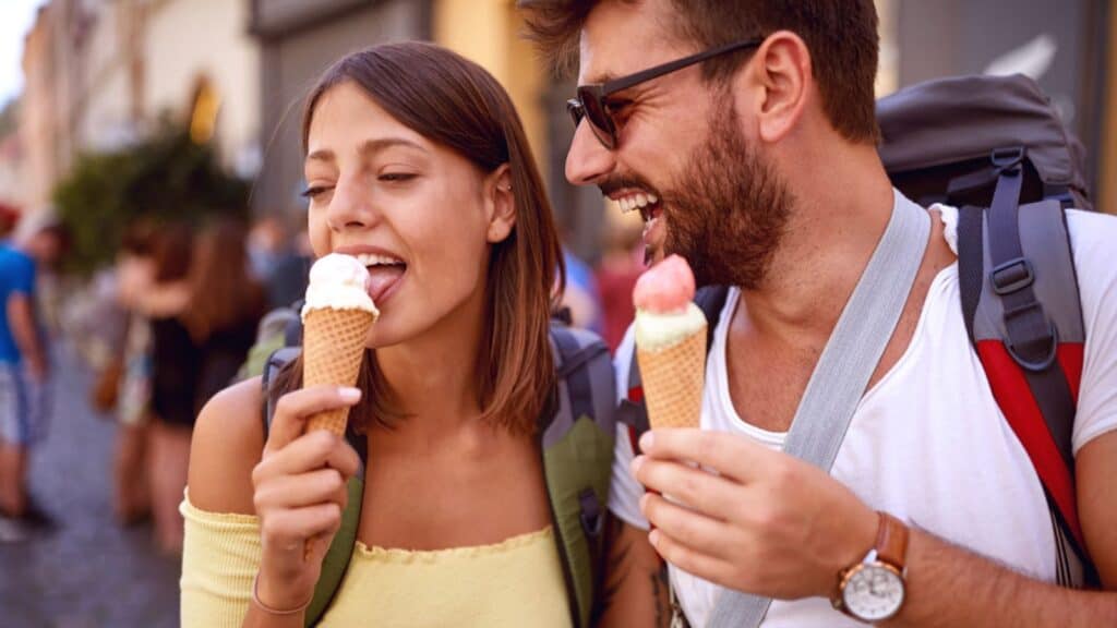 Young tourist couple enjoying the ice cream at city streets on a beautiful weather