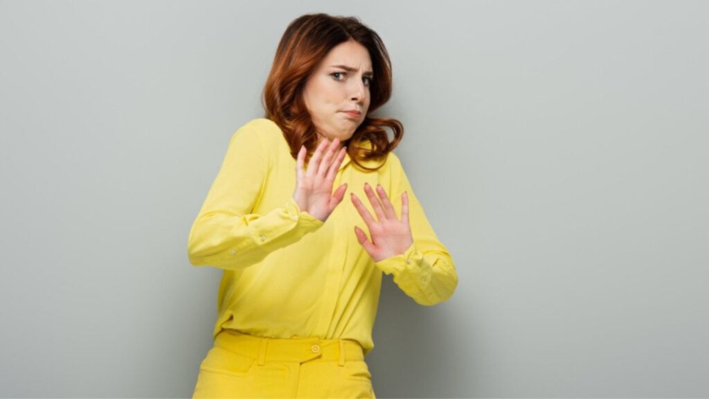 Young woman feeling disgust and showing refuse gesture