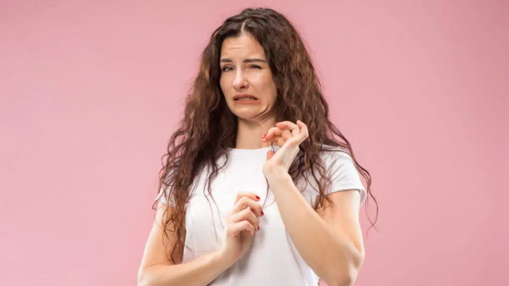 Young woman with disgusted expression repulsing on pink background