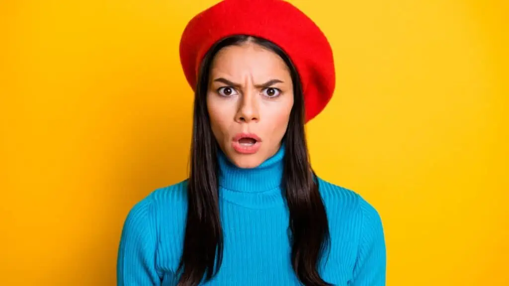 annoyed disgusted woman wearing red hat yellow background