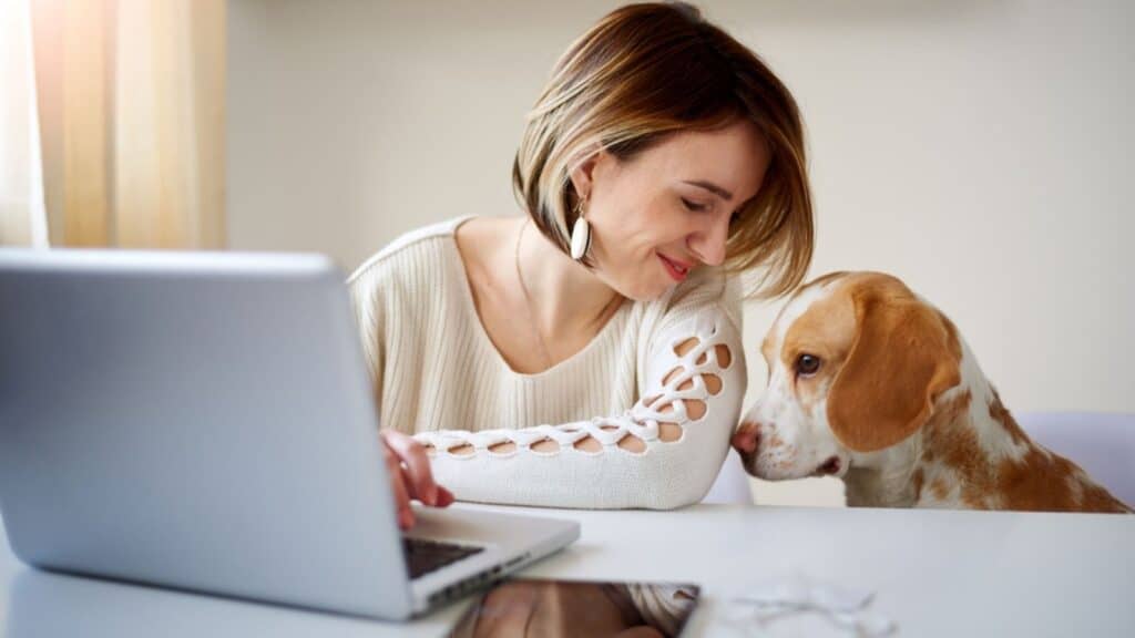 woman working at computer desk with her dog