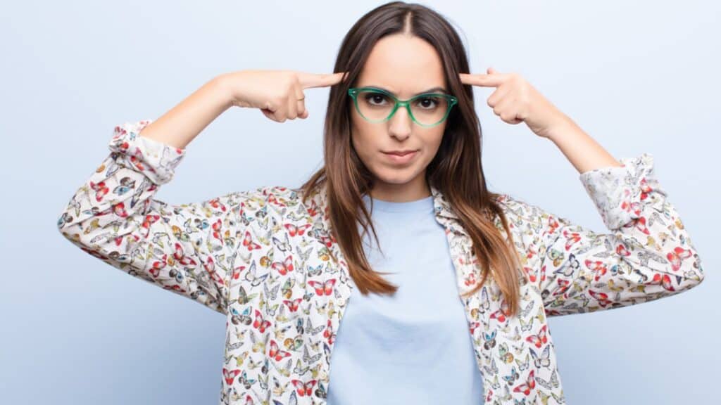 confused woman in glasses pointing to her head