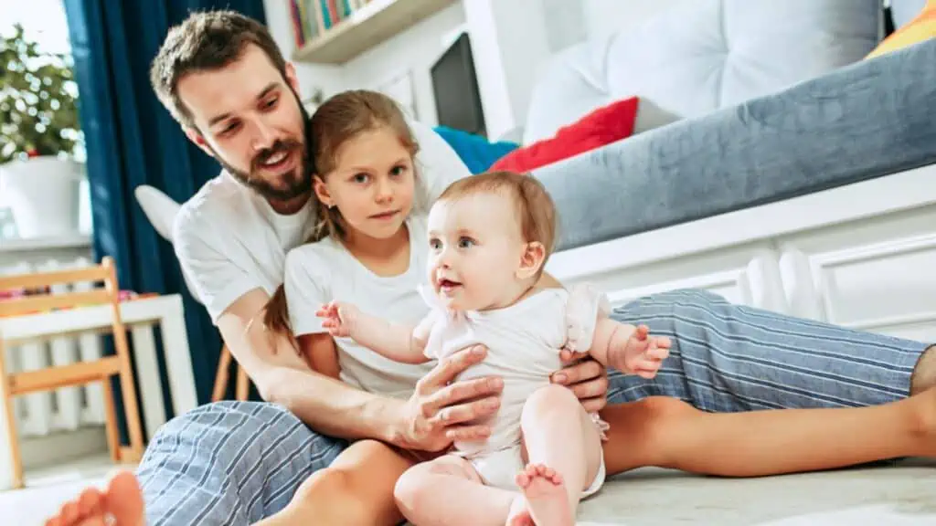 dad with daughters girl and baby living room floor