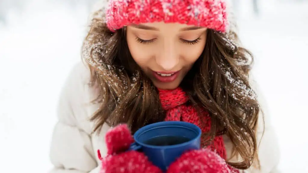 woman in winter hat and mittens with coffee or hot coco