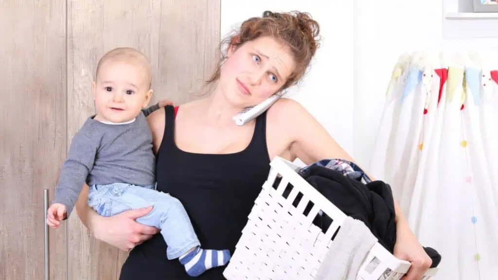 overwhelmed mom with a baby and laundry basket