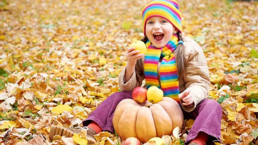 girl in the fall eating apples pumpkin happy