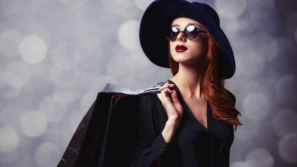 woman in a black hat sunglasses shopping rich affluent lipstick
