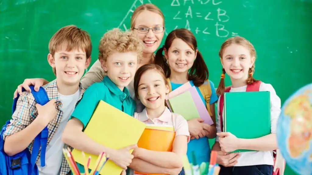 kids in school with a teacher notebook chalk board