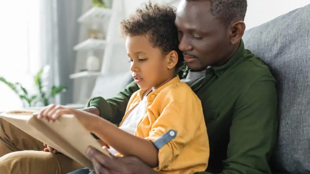 dad and son (boy) reading a book on the couch